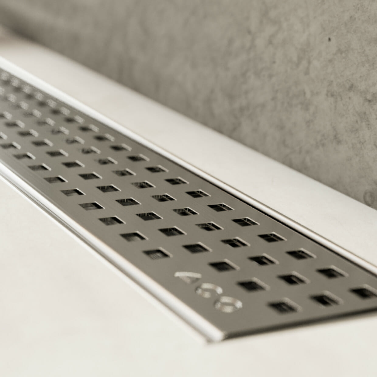 Nahaufnahme der ACO ShowerDrain C Duschrinne mit Quadrato Designrost in gefliestem Duschbereich vor Betonwand