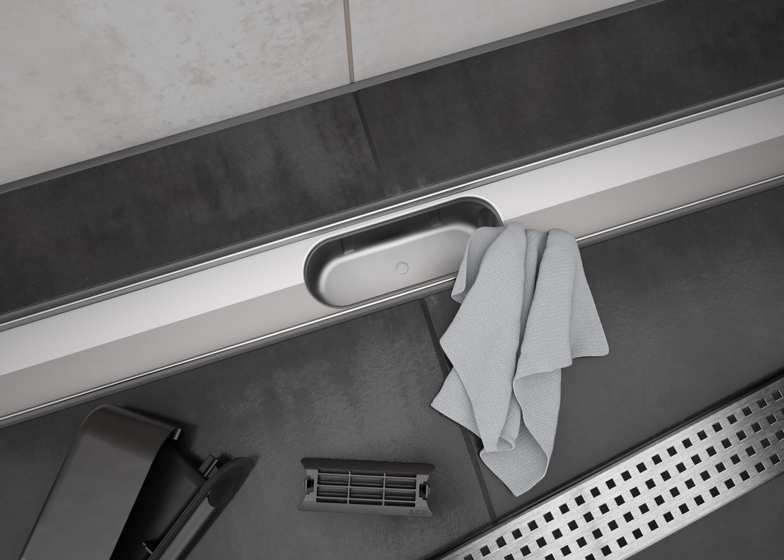 ACO ShowerDrain C Duschrinne bei der Reinigung, mit entferntem Geruchsverschluss, Tuch und Haarsieb auf dunklen Fliesen